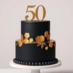 Elegant gold and black 50th birthday cake with gold leaf accents and a sophisticated topper