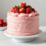 Beautifully styled strawberry cake with fresh berries and pink frosting on a white cake stand for Pinterest photography