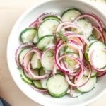 Bowl of creamy cucumber salad with thin slices of cucumber and red onion in a creamy dill dressing