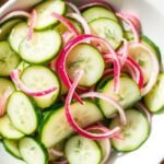 Easy cucumber salad in a white bowl with thin cucumber slices, red onion, and fresh dill