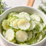 Traditional German cucumber salad (Gurkensalat) served in a white bowl with fresh dill garnish