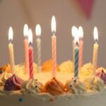 A beautifully decorated birthday cake with lit candles and colorful decorations against a soft background, representing heartfelt birthday celebrations