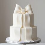 Elegant white wedding cake with a large fondant bow cake design on top tier