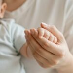 Mother holding her baby son's hand, symbolizing the beginning of their journey together on his happy birthday