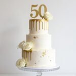 elegant gold 50th birthday cake with gold leaf accents and white fondant