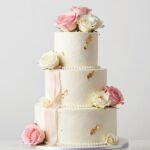 elegant multi-tier white birthday cake with fresh roses and gold accents for sophisticated lady celebration