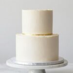 modern minimalist birthday cake with clean white frosting and single gold accent